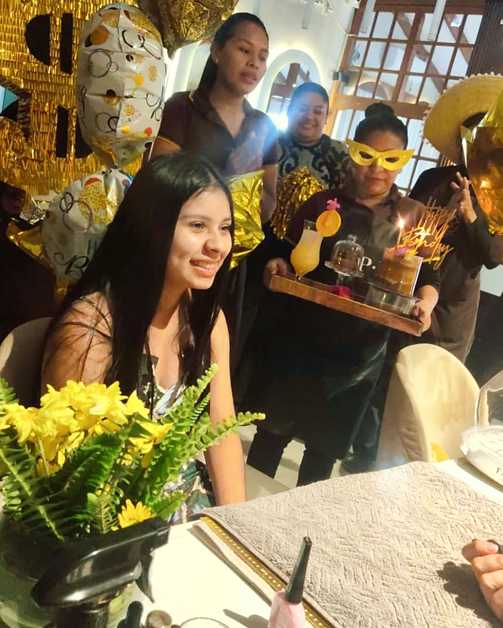 Clienta festejando su cumpleaños en Eurosmética, con el equipo llevándole la torta con chispero
